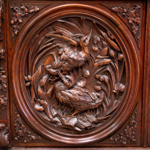 fig 1. A 19th-century French dark oak two-tier hunting cabinet featuring glazed upper doors and deeply carved lower panels depicting game birds.