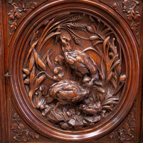 fig 2. A 19th-century French dark oak two-tier hunting cabinet featuring glazed upper doors and deeply carved lower panels depicting game birds.