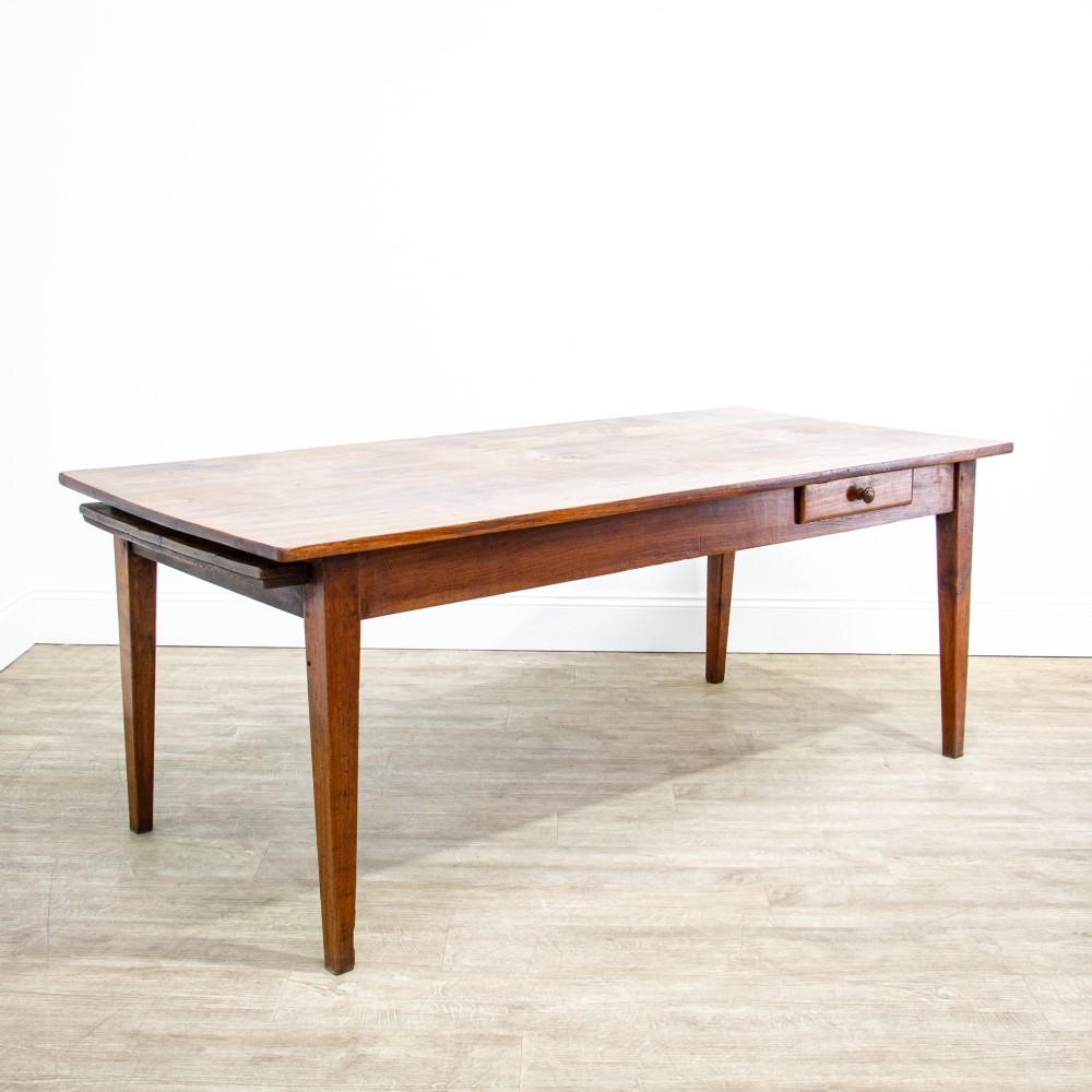 A 19th-century French fruitwood farmhouse dining table featuring a rectangular plank top, tapered square legs, and a single frieze drawer.