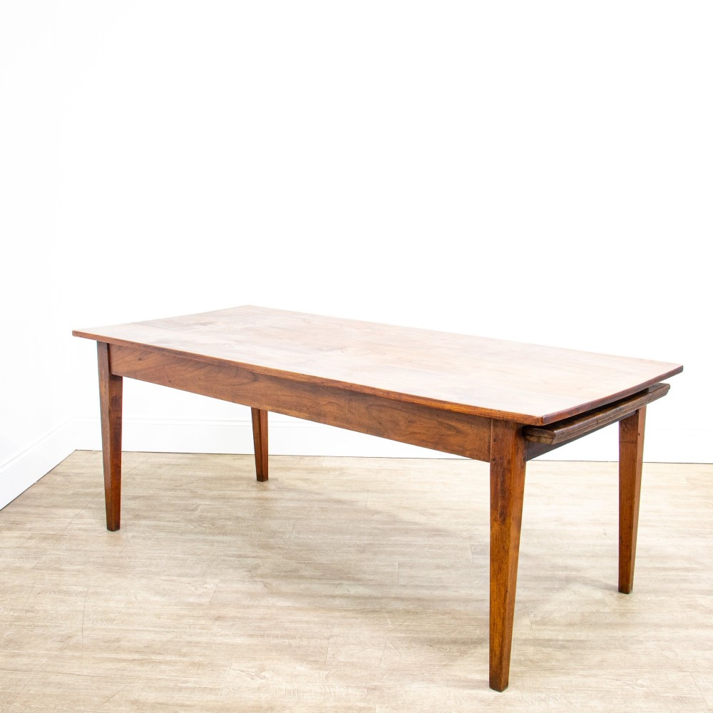 A 19th-century French fruitwood farmhouse dining table featuring a rectangular plank top, tapered square legs, and a single frieze drawer. View VII