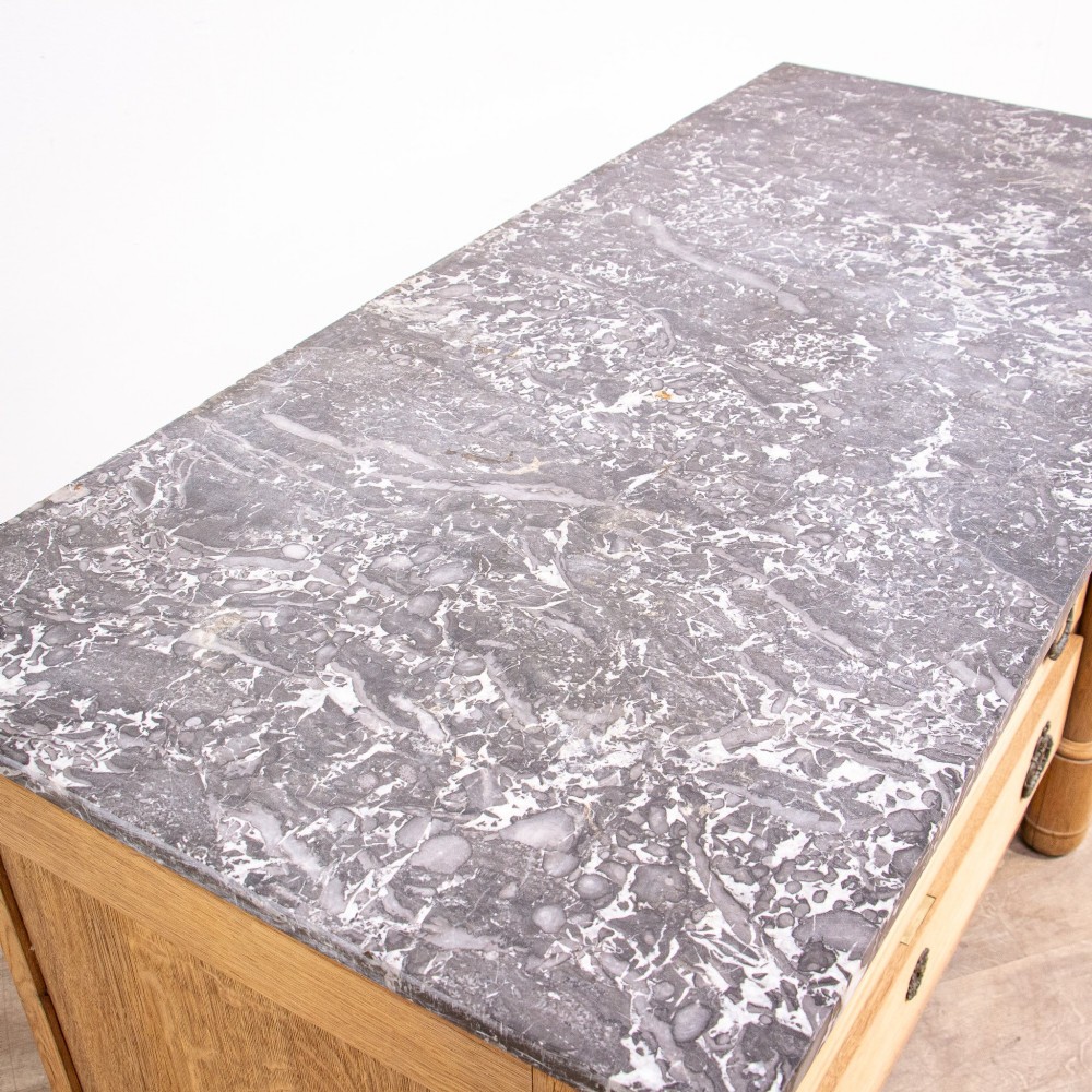 A nineteenth-century bleached oak French Empire commode featuring four drawers, flanking columns, brass ring pull handles, and a dark grey marble top. View IV
