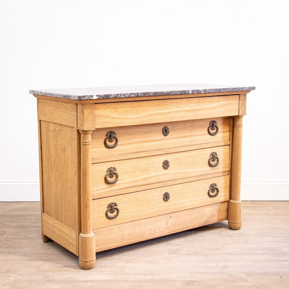 A nineteenth-century bleached oak French Empire commode featuring four drawers, flanking columns, brass ring pull handles, and a dark grey marble top. View XIII