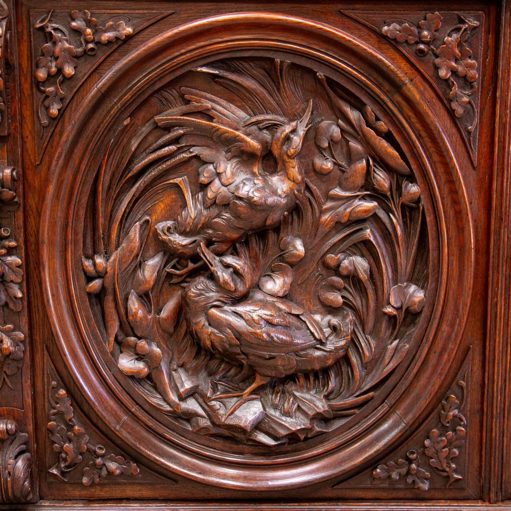 A 19th-century French dark oak two-tier hunting cabinet featuring glazed upper doors and deeply carved lower panels depicting game birds. View II