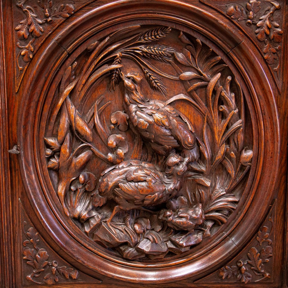 A 19th-century French dark oak two-tier hunting cabinet featuring glazed upper doors and deeply carved lower panels depicting game birds. View III