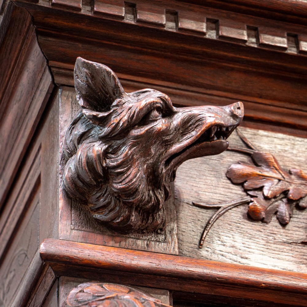 A 19th-century French dark oak two-tier hunting cabinet featuring glazed upper doors and deeply carved lower panels depicting game birds. View IV