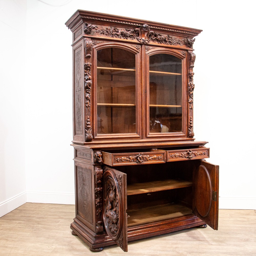 A 19th-century French dark oak two-tier hunting cabinet featuring glazed upper doors and deeply carved lower panels depicting game birds. View VI
