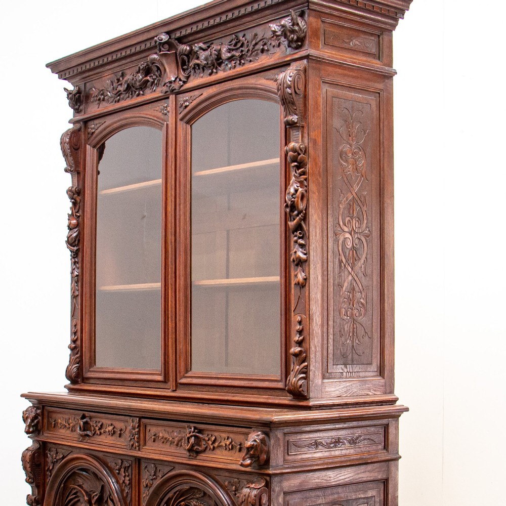 A 19th-century French dark oak two-tier hunting cabinet featuring glazed upper doors and deeply carved lower panels depicting game birds. View IX