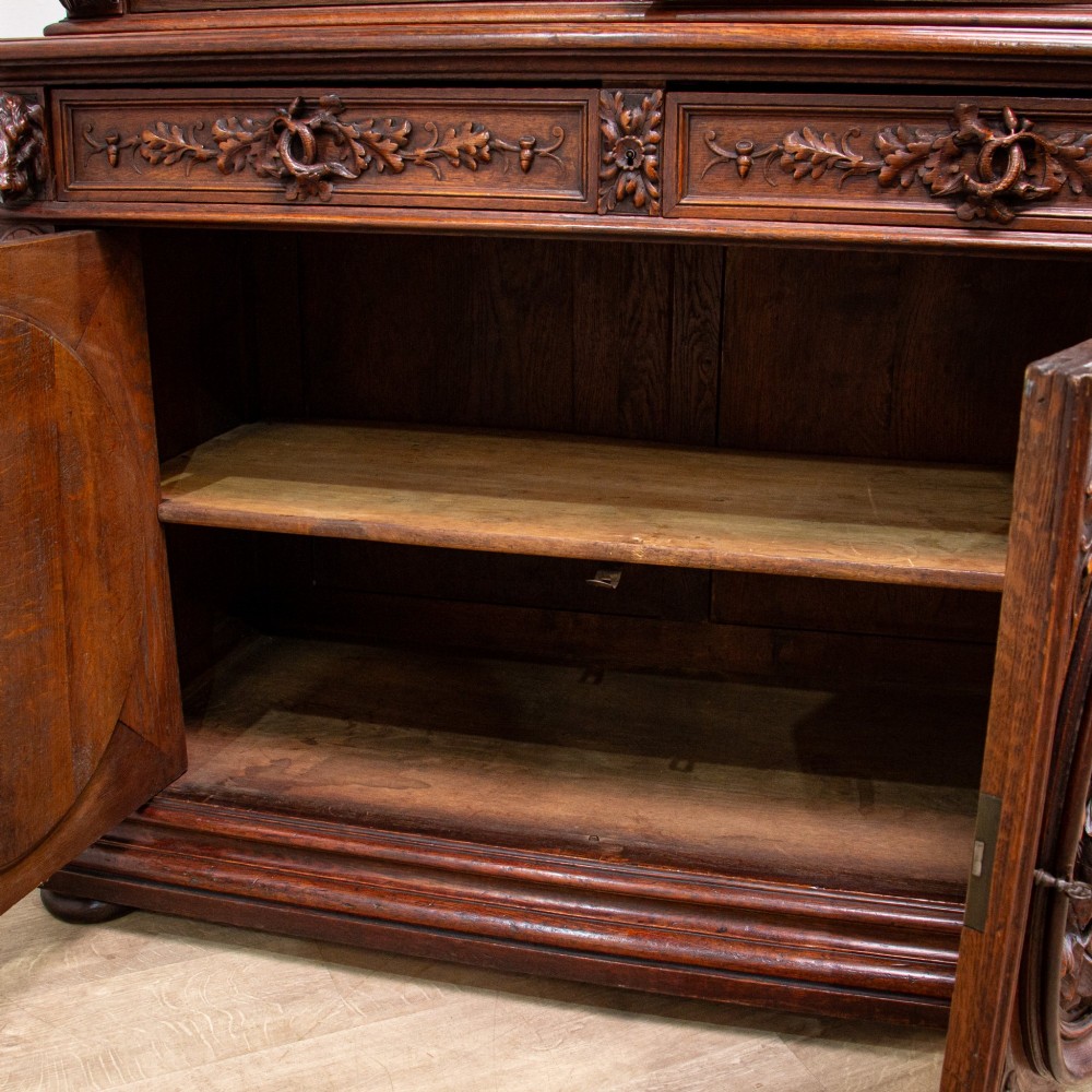 A 19th-century French dark oak two-tier hunting cabinet featuring glazed upper doors and deeply carved lower panels depicting game birds. View XII