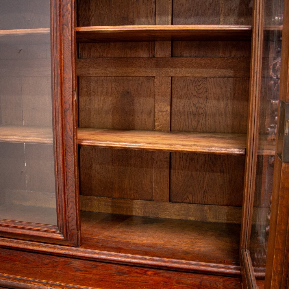A 19th-century French dark oak two-tier hunting cabinet featuring glazed upper doors and deeply carved lower panels depicting game birds. View XIV
