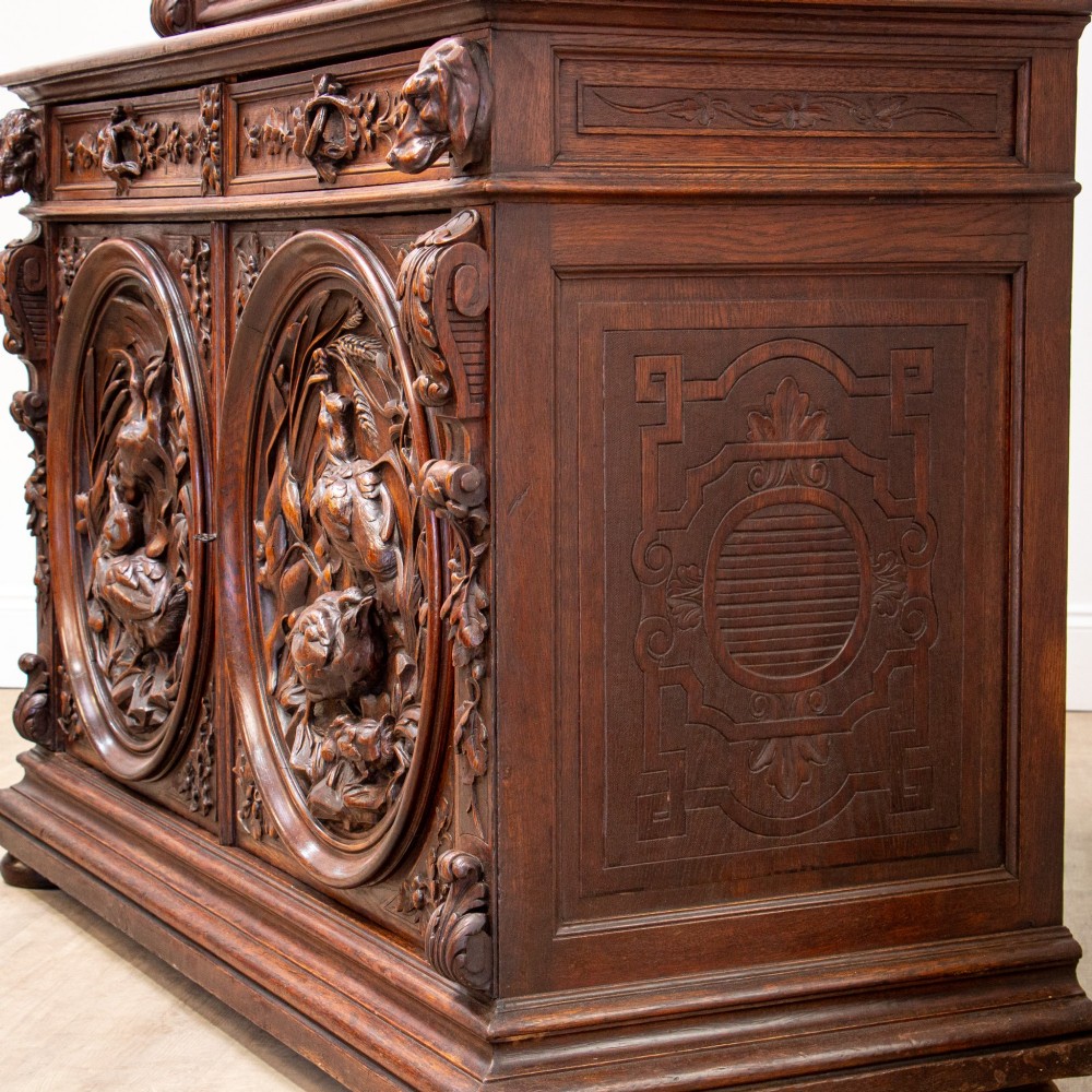 A 19th-century French dark oak two-tier hunting cabinet featuring glazed upper doors and deeply carved lower panels depicting game birds. View XV
