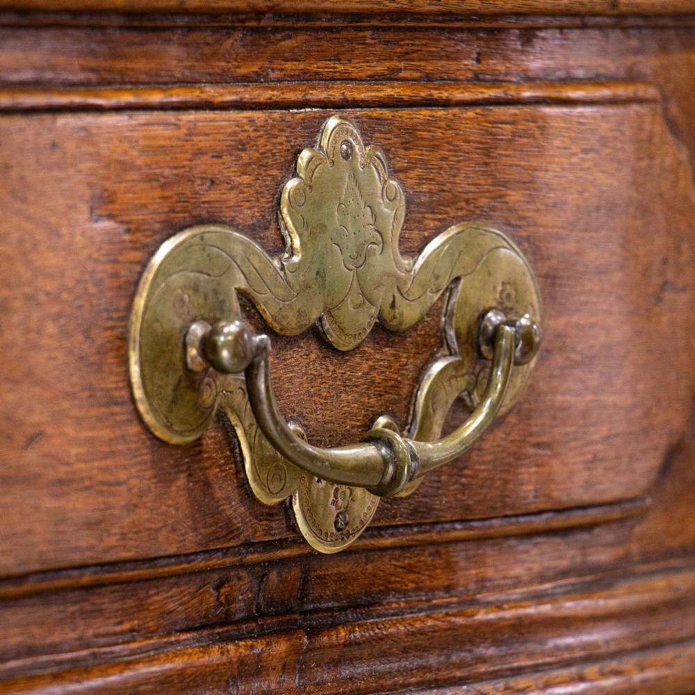 An 18th-century French Louis XV oak commode featuring three serpentine drawers with carved moulded panels, ornate brass handles, and carved cabriole legs. View III