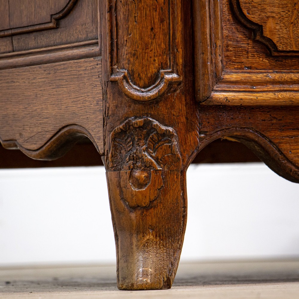 An 18th-century French Louis XV oak commode featuring three serpentine drawers with carved moulded panels, ornate brass handles, and carved cabriole legs. View VII