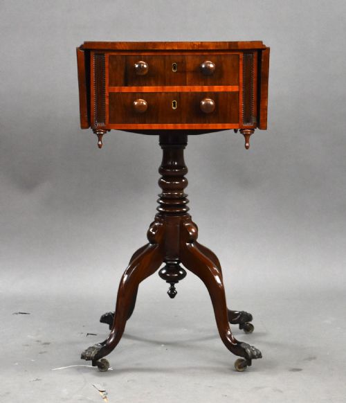 fig 1. A Regency mahogany work table featuring drop leaves, two drawers with round wooden knobs, a turned central pedestal column, and four splayed legs with brass castors.