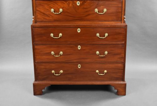fig 2. A George III mahogany chest on chest featuring multiple stacked drawers with flame mahogany veneer, brass handles, and bracket feet.