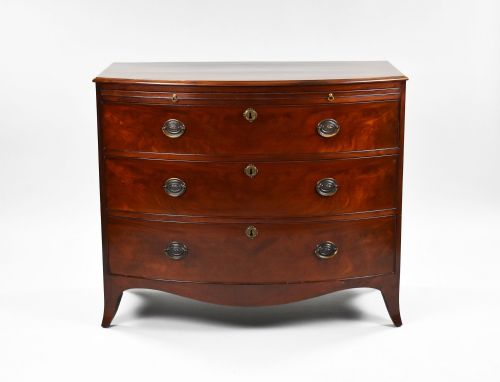 fig 1. A Regency mahogany bow-front chest of drawers featuring three graduated drawers with brass oval handles and splayed bracket feet.