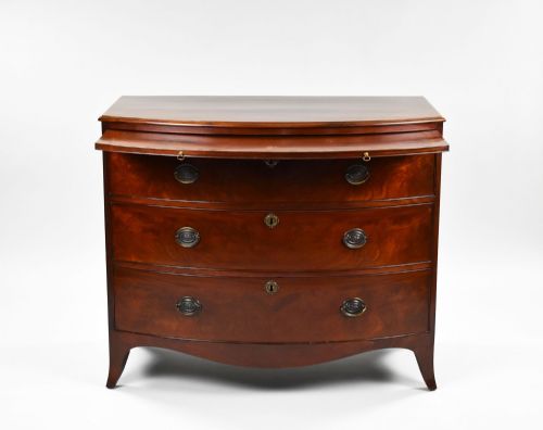 fig 2. A Regency mahogany bow-front chest of drawers featuring three graduated drawers with brass oval handles and splayed bracket feet.