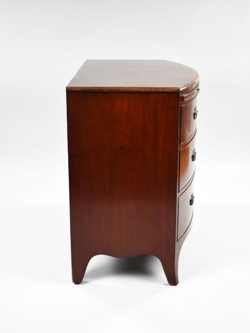 fig 3. A Regency mahogany bow-front chest of drawers featuring three graduated drawers with brass oval handles and splayed bracket feet.