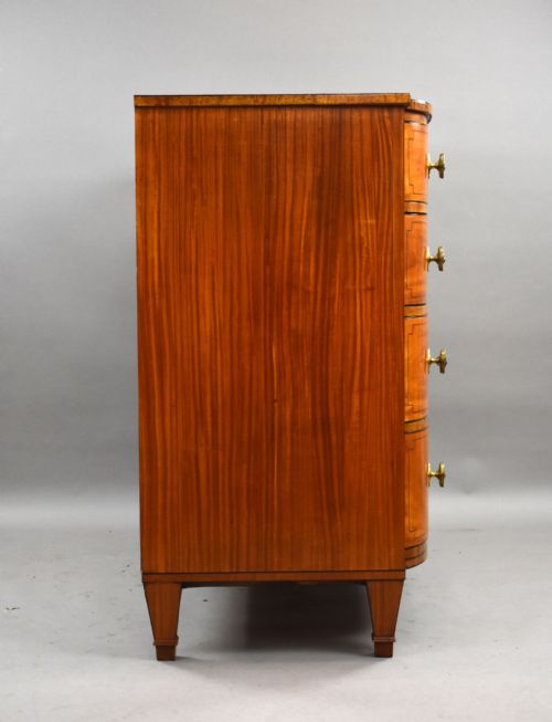 fig 3. A Regency period bowfront chest of four graduated drawers constructed from golden satinwood with crossbanded borders and turned brass knobs.