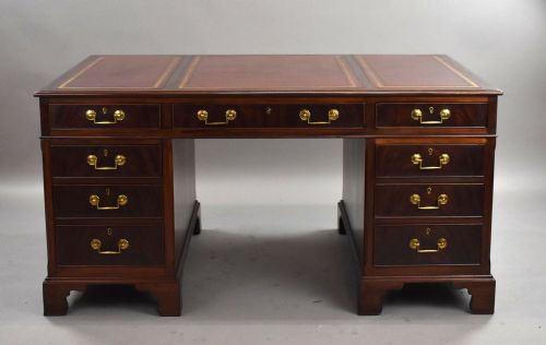fig 1. An Edwardian mahogany pedestal desk featuring a three-panel red gilt-tooled leather writing top, nine drawers with brass handles, and bracket feet.