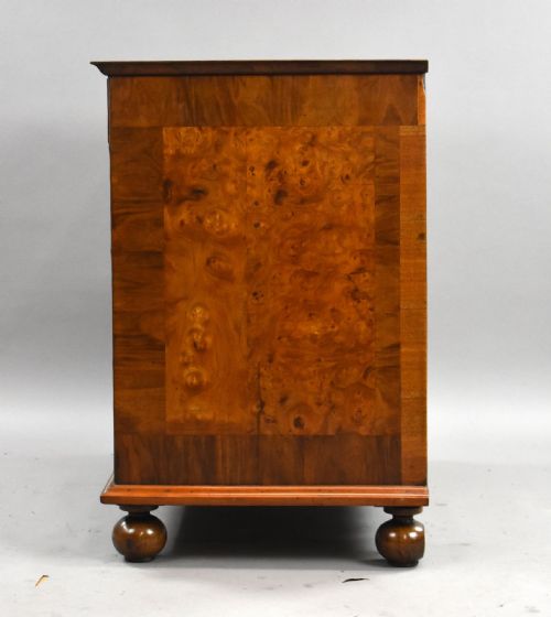 fig 2. A William and Mary burr walnut chest featuring intricate dark marquetry inlay panels, brass swing handles, and turned bun feet.