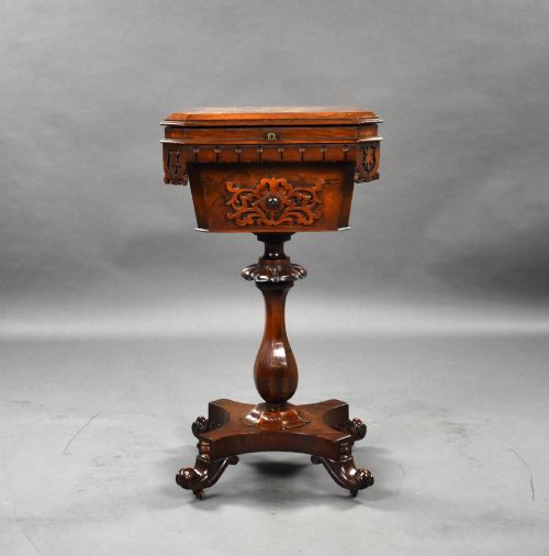 fig 1. A William IV rosewood tea poy featuring a hinged lidded box top, carved openwork scrolls, a turned pedestal column, and a four-point base with scroll feet.