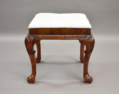 fig 1. A square Queen Anne style walnut stool featuring cream textured fabric upholstery and carved cabriole legs with shell motifs.