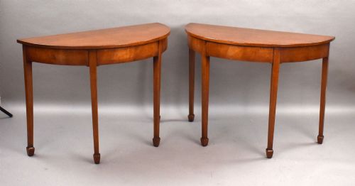 fig 1. A pair of Georgian mahogany demilune console tables featuring semi-circular tops, plain aprons, and square tapered legs.