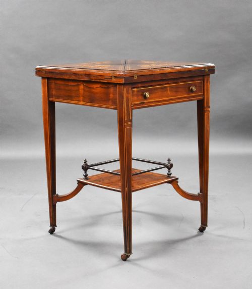 fig 1. An Edwardian inlaid rosewood envelope card table with tapered square legs, brass castors, a lower undertier shelf, and a top split into four triangular leaves.