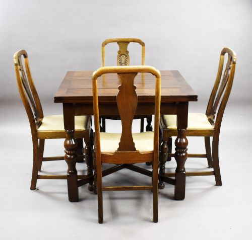 fig 1. An antique warm brown oak draw-leaf dining table surrounded by four matching carved wooden chairs with light upholstery.