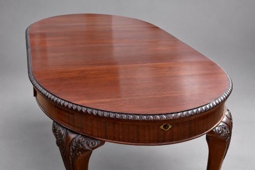 fig 6. An Edwardian mahogany extending dining table surrounded by matching Chippendale style dining chairs with striped upholstered seats and carved ball and claw feet.