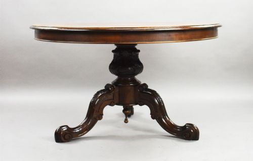 fig 2. A Victorian circular burr walnut centre table featuring floral marquetry inlays on the tabletop and a dark carved pedestal base.