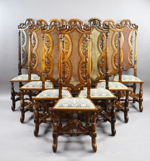 fig 1. A long dark oak refectory style dining table surrounded by ten high-back carved oak chairs with woven cane back panels and patterned upholstered seats.