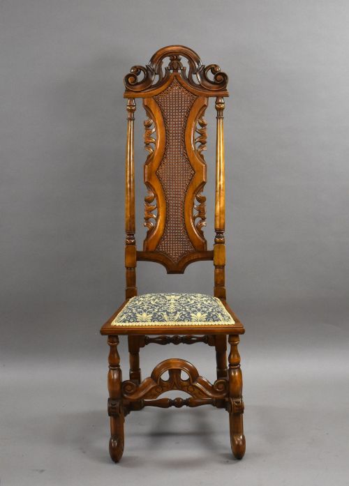 fig 3. A long dark oak refectory style dining table surrounded by ten high-back carved oak chairs with woven cane back panels and patterned upholstered seats.