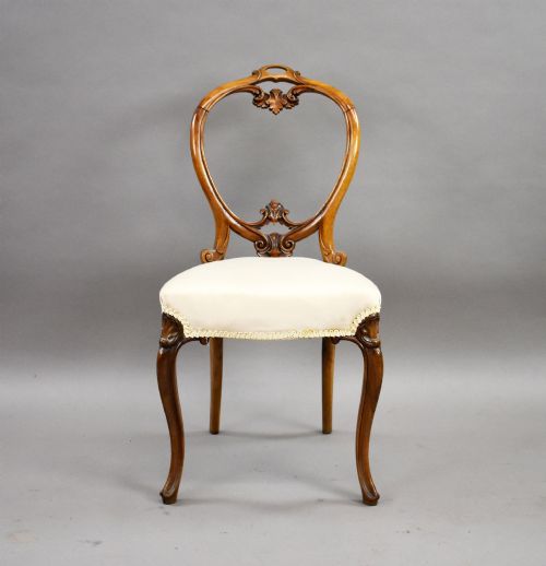 fig 2. A set of four Victorian walnut balloon back dining chairs featuring carved back crests, cabriole front legs, and cream upholstered seats.
