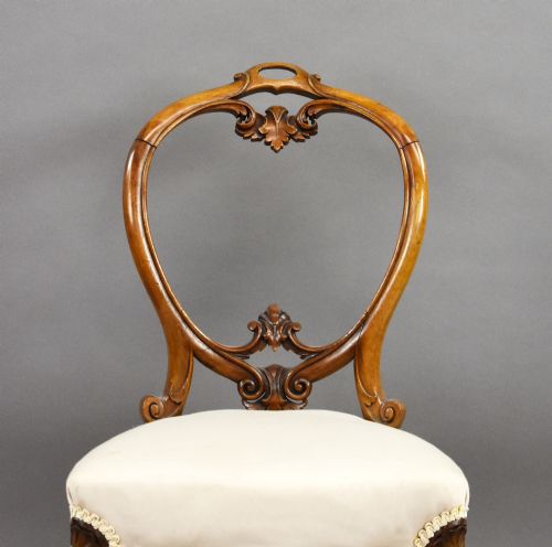 fig 3. A set of four Victorian walnut balloon back dining chairs featuring carved back crests, cabriole front legs, and cream upholstered seats.