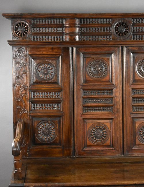 fig 3. A high-backed dark oak panelled settle featuring geometric roundel carvings, a spindle frieze, scroll arms, and a box seat storage base.