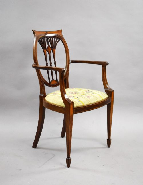 fig 1. A pair of Edwardian Sheraton Revival mahogany armchairs featuring oval backs with vertical fan splats, swept arms, satinwood inlays, and yellow floral upholstered seats.