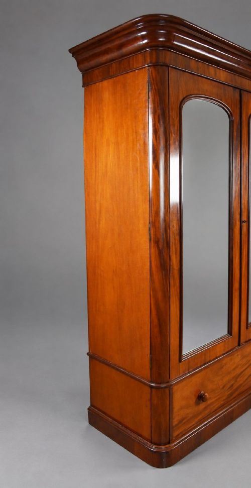 fig 1. A nineteenth-century Victorian mahogany wardrobe featuring two arched mirrored doors above a single full-width drawer with turned wooden knobs.