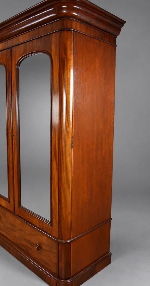 fig 2. A nineteenth-century Victorian mahogany wardrobe featuring two arched mirrored doors above a single full-width drawer with turned wooden knobs.
