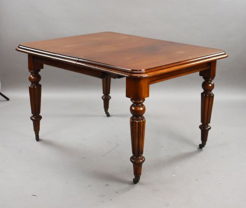 fig 1. A Victorian mahogany extending dining table featuring fluted turned legs set on brass castors.