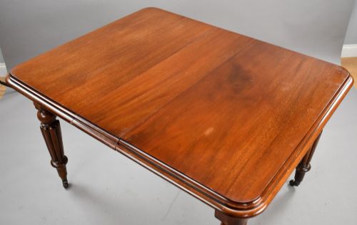fig 3. A Victorian mahogany extending dining table featuring fluted turned legs set on brass castors.