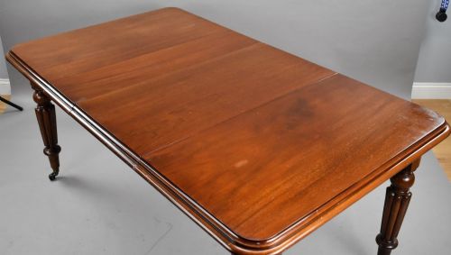fig 4. A Victorian mahogany extending dining table featuring fluted turned legs set on brass castors.