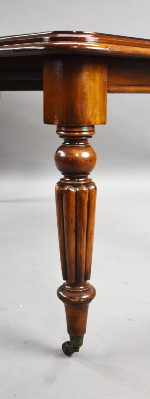 A Victorian mahogany extending dining table featuring fluted turned legs set on brass castors. View VI