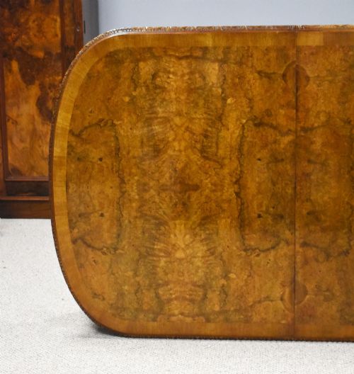 fig 4. A Queen Anne style burr walnut extending dining table shown with eight matching chairs featuring curved backrests and floral upholstered seats.