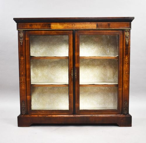 fig 1. A Victorian mahogany pier cabinet featuring two glazed doors, floral marquetry inlay, gilt-bronze mounts, and a fabric-lined interior with shelves.
