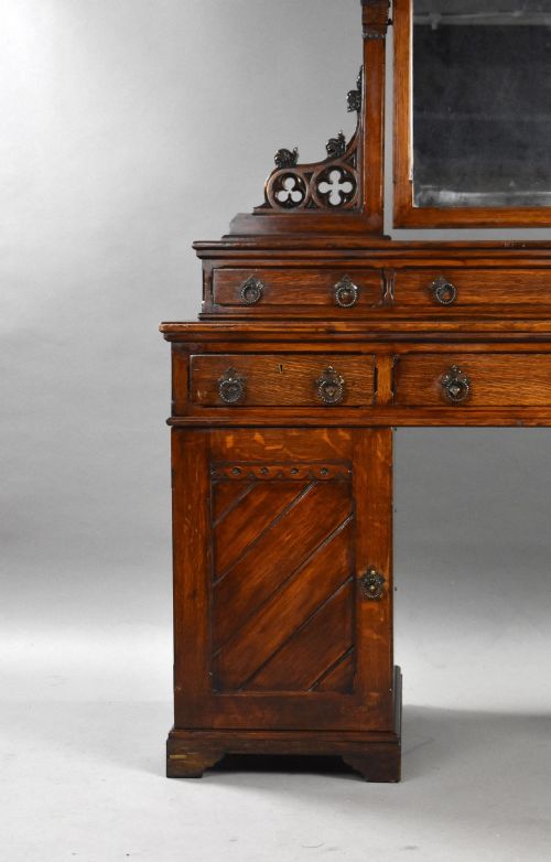 fig 1. A Victorian Gothic Revival oak dressing table featuring a central pointed arched mirror, trefoil tracery carvings, multiple drawers, and pedestal cupboards with diagonal wood panelling.