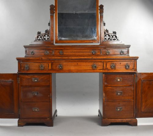 fig 3. A Victorian Gothic Revival oak dressing table featuring a central pointed arched mirror, trefoil tracery carvings, multiple drawers, and pedestal cupboards with diagonal wood panelling.
