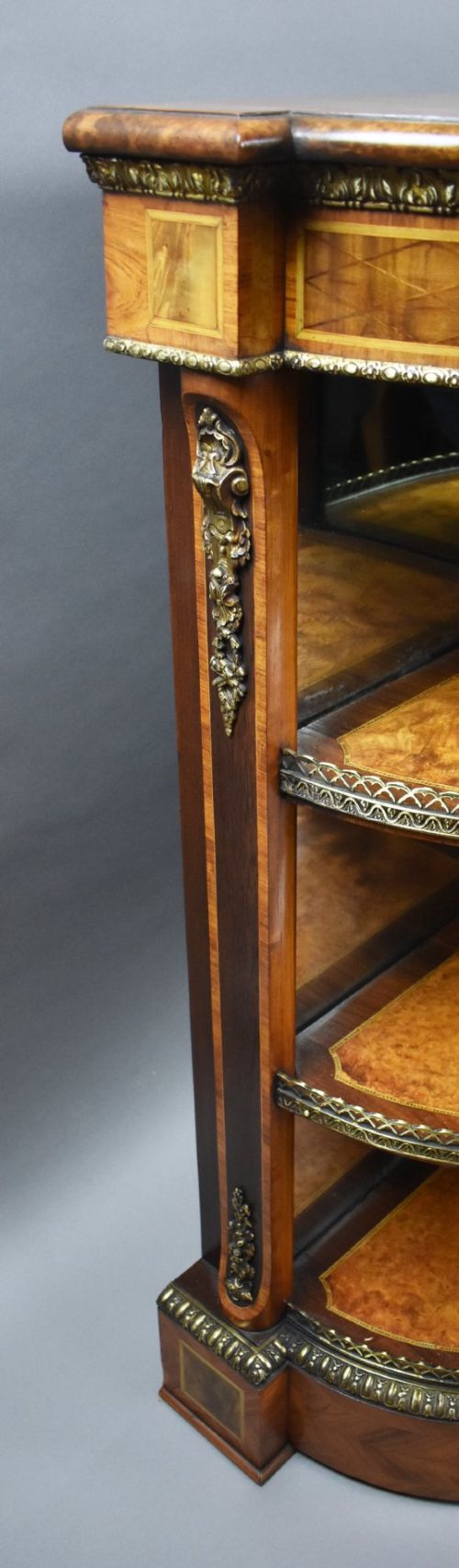 A Victorian burr walnut credenza featuring central cupboard doors with oval porcelain plaques and gilt bronze mounts flanked by curved open display shelves. View VII