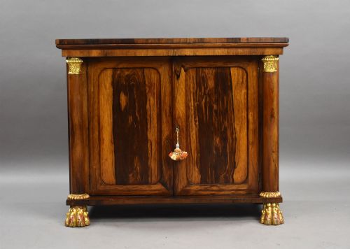 fig 1. A 19th-century Regency rosewood side cabinet featuring two panelled doors, flanking column supports, and carved giltwood lion paw feet.