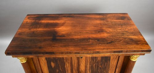 fig 4. A 19th-century Regency rosewood side cabinet featuring two panelled doors, flanking column supports, and carved giltwood lion paw feet.